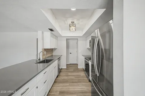 a hallway with white cabinets and stainless steel appliances