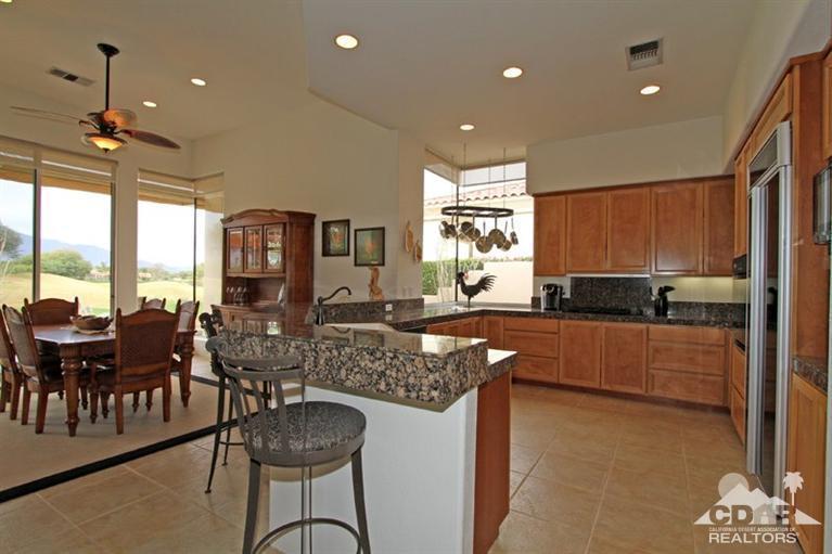 178 Loch Lomond Road Rancho Mirage, CA 92270 - Photo 13 of 32 a kitchen with granite countertop a stove a sink a dining table and chairs