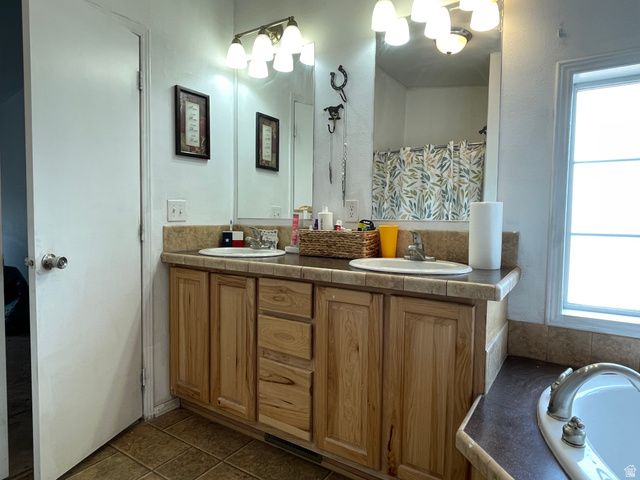240 Horseshoe Bend Road Vernal, UT 84078 - Photo 16 of 41 Full bathroom with double vanity, curtained shower, dark tile patterned floors, and a soaking tub