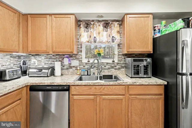 a kitchen with stainless steel appliances granite countertop a sink a stove a refrigerator with white cabinets and wooden floor