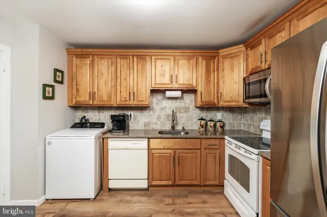 a kitchen with stainless steel appliances granite countertop a refrigerator stove a sink dishwasher and microwave with wooden cabinets