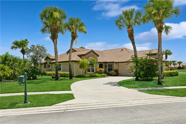 a view of a house with a yard and palm trees