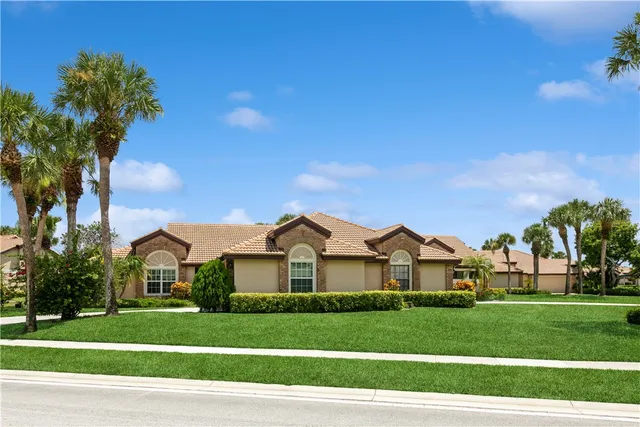 a view of a white house with a big yard and large trees