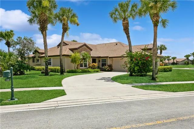 a front view of a house with a yard and palm trees