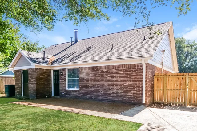 a view of a back yard of the house with a large tree