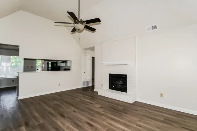 a view of a livingroom with a fireplace a ceiling fan and wooden floor