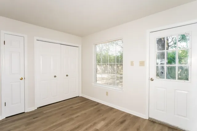 a view of an empty room with wooden floor and a window