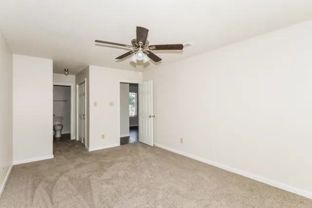 an empty room with closet and a ceiling fan