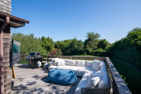 a view of patio with couches table and chairs under an umbrella with a small yard