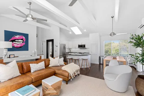 a living room with furniture kitchen view and a chandelier