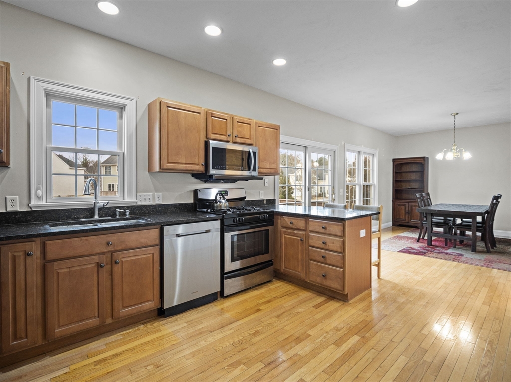 36 Knowlton Circle, Unit 1 Upton, MA 01568 - Photo 7 of 37 a kitchen with stainless steel appliances granite countertop a stove top oven a sink dishwasher a dining table and chairs with wooden floor