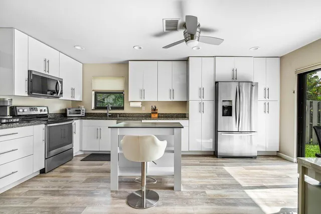 a kitchen with granite countertop a refrigerator stove top oven and sink