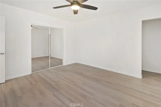 an empty room with wooden floor fan and windows