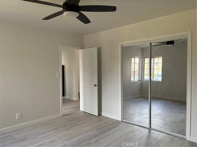 a view of empty room with wooden floor and fan