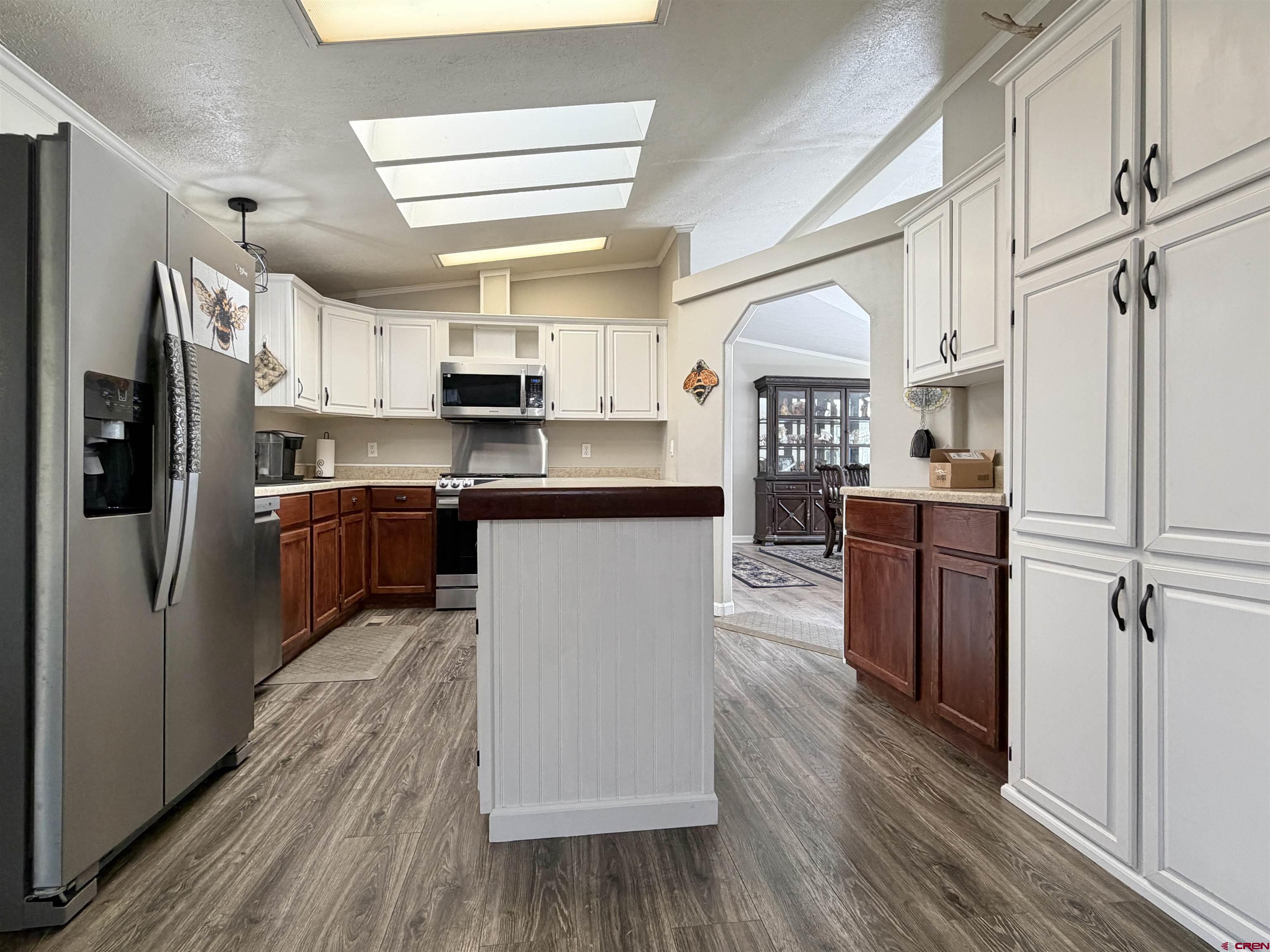 650 1725th Road Delta, CO 81416 - Photo 11 of 45 a kitchen with stainless steel appliances granite countertop a refrigerator a sink dishwasher a stove with wooden floor and cabinets next to a window