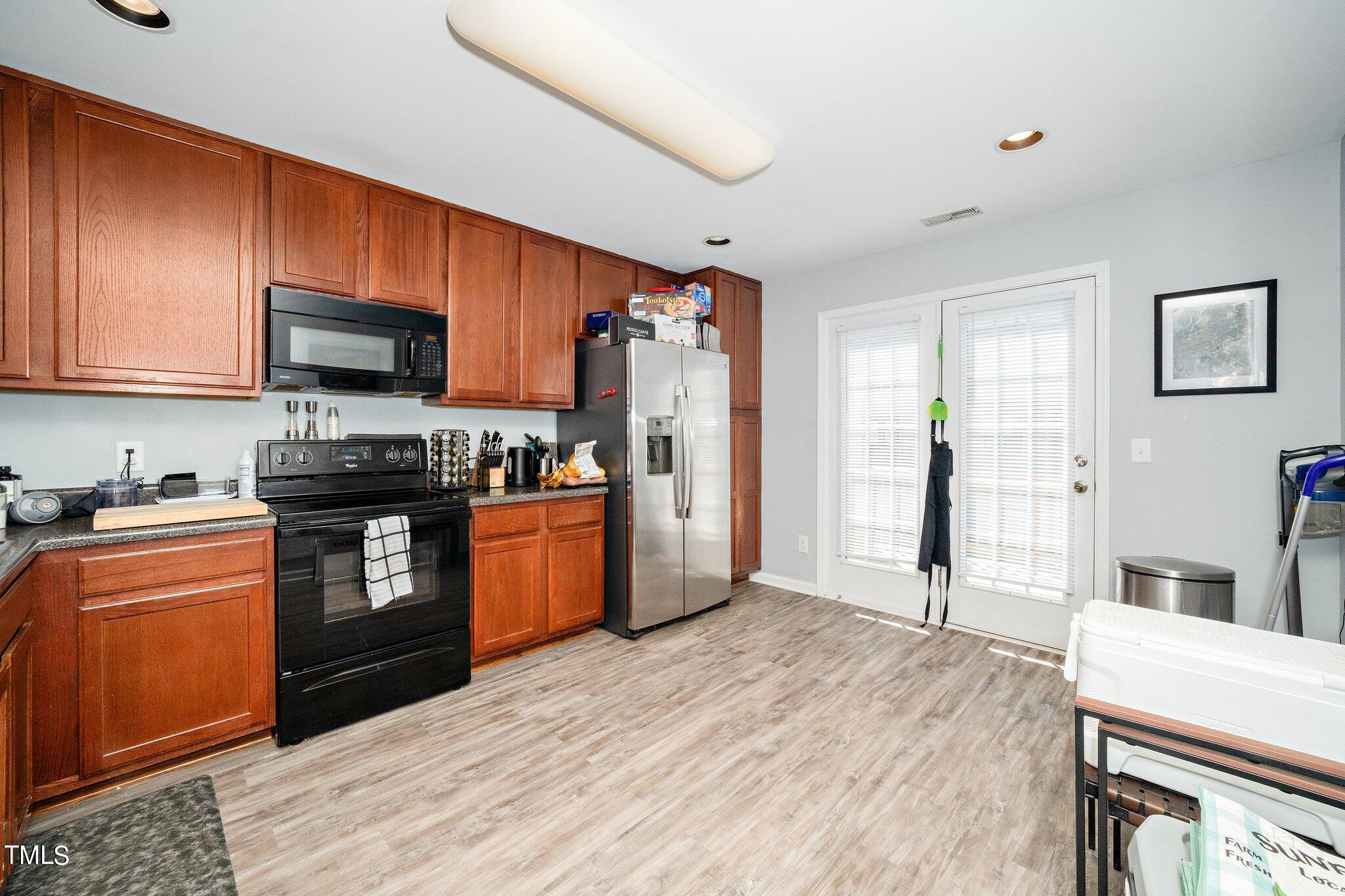9813 Cicero Drive Raleigh, NC 27617 - Photo 5 of 21 a kitchen with granite countertop wooden floors stainless steel appliances and sink