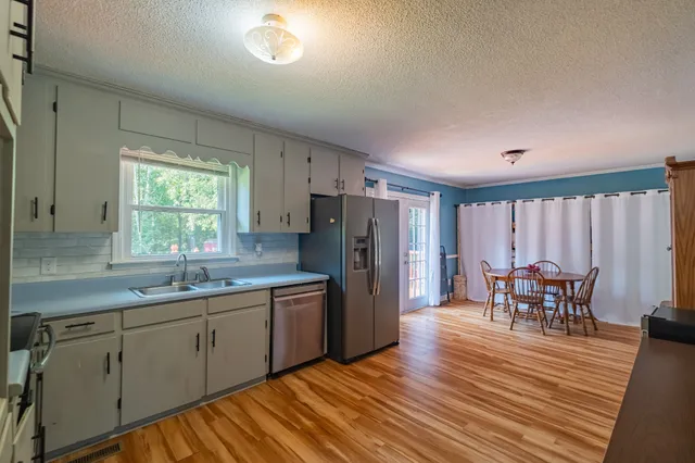 a kitchen with stainless steel appliances granite countertop a dining table chairs and a refrigerator