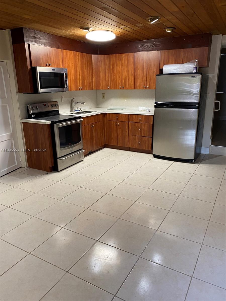 1051 Southwest 3rd Street, Unit 3 Miami, FL 33130 - Photo 4 of 8 a kitchen with kitchen island granite countertop a stove a sink and a microwave