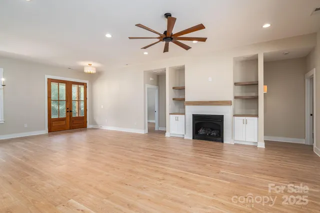 a view of a livingroom with a ceiling fan a fireplace and a window