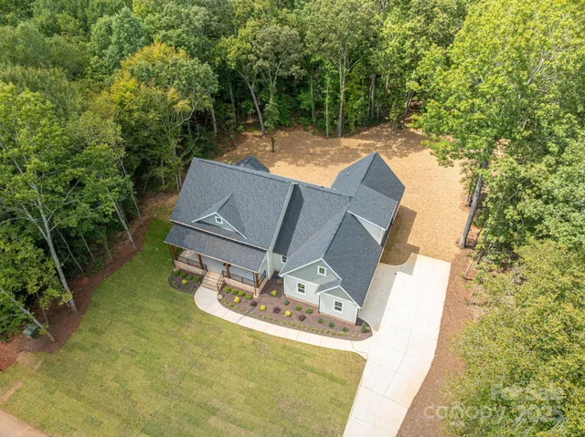 an aerial view of house with yard and trees in the background