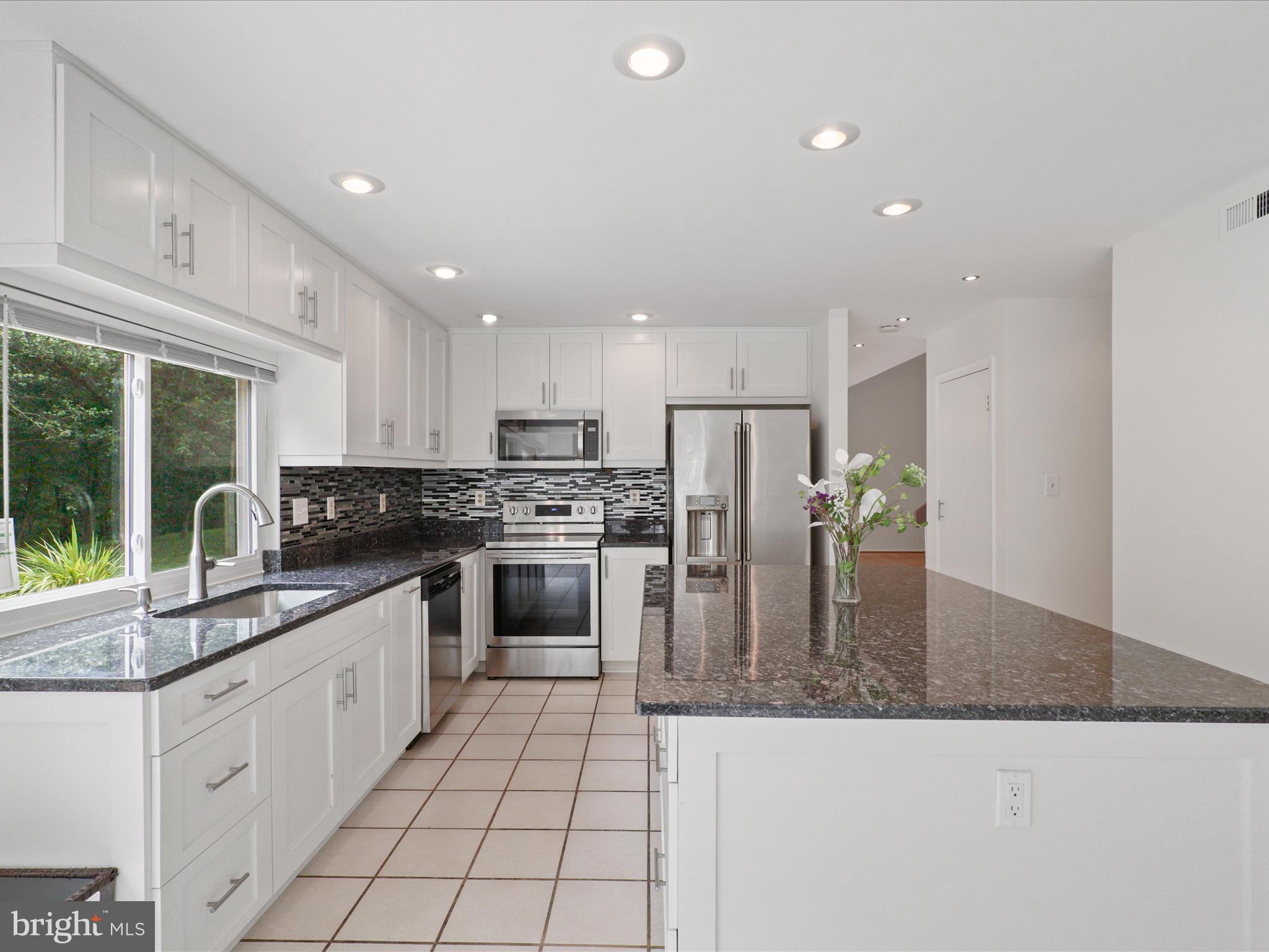 5922 Hall Street Springfield, VA 22152 - Photo 16 of 47 a kitchen with kitchen island granite countertop a stove a sink a refrigerator and white cabinets with wooden floor