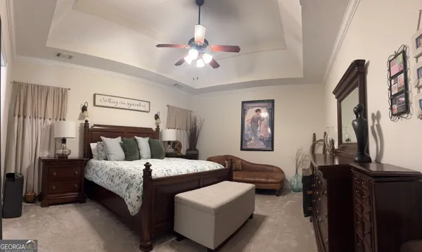 a bedroom with a bed couches and a flat tv screen