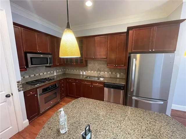 a kitchen with stainless steel appliances granite countertop a stove a refrigerator a sink a oven with wooden cabinets and wooden floor