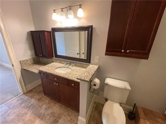 a bathroom with a granite countertop toilet sink and mirror
