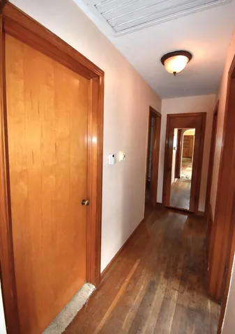 a view of a hallway with wooden floor and a bathroom