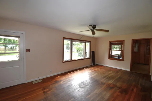 a view of an empty room with a window and wooden floor