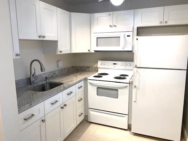 a kitchen with granite countertop white cabinets and white appliances
