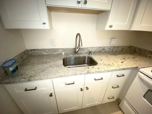a kitchen with granite countertop a sink a stove and cabinets