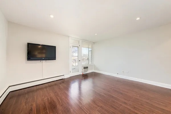 a view of an empty room with wooden floor and windows