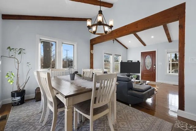 a dining room with wooden floor a chandelier a wooden table and chairs