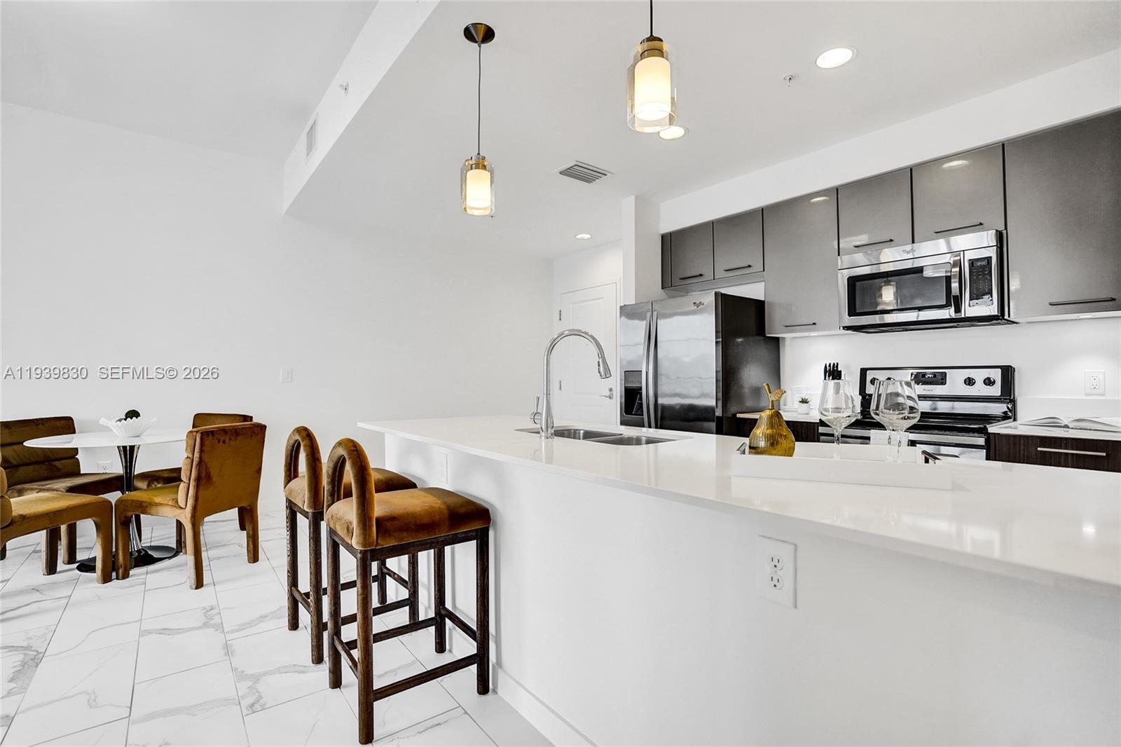 101 East Camino Real, Unit PH07 Boca Raton, FL 33432 - Photo 34 of 43 a kitchen with stainless steel appliances a sink a stove a refrigerator cabinets and chairs