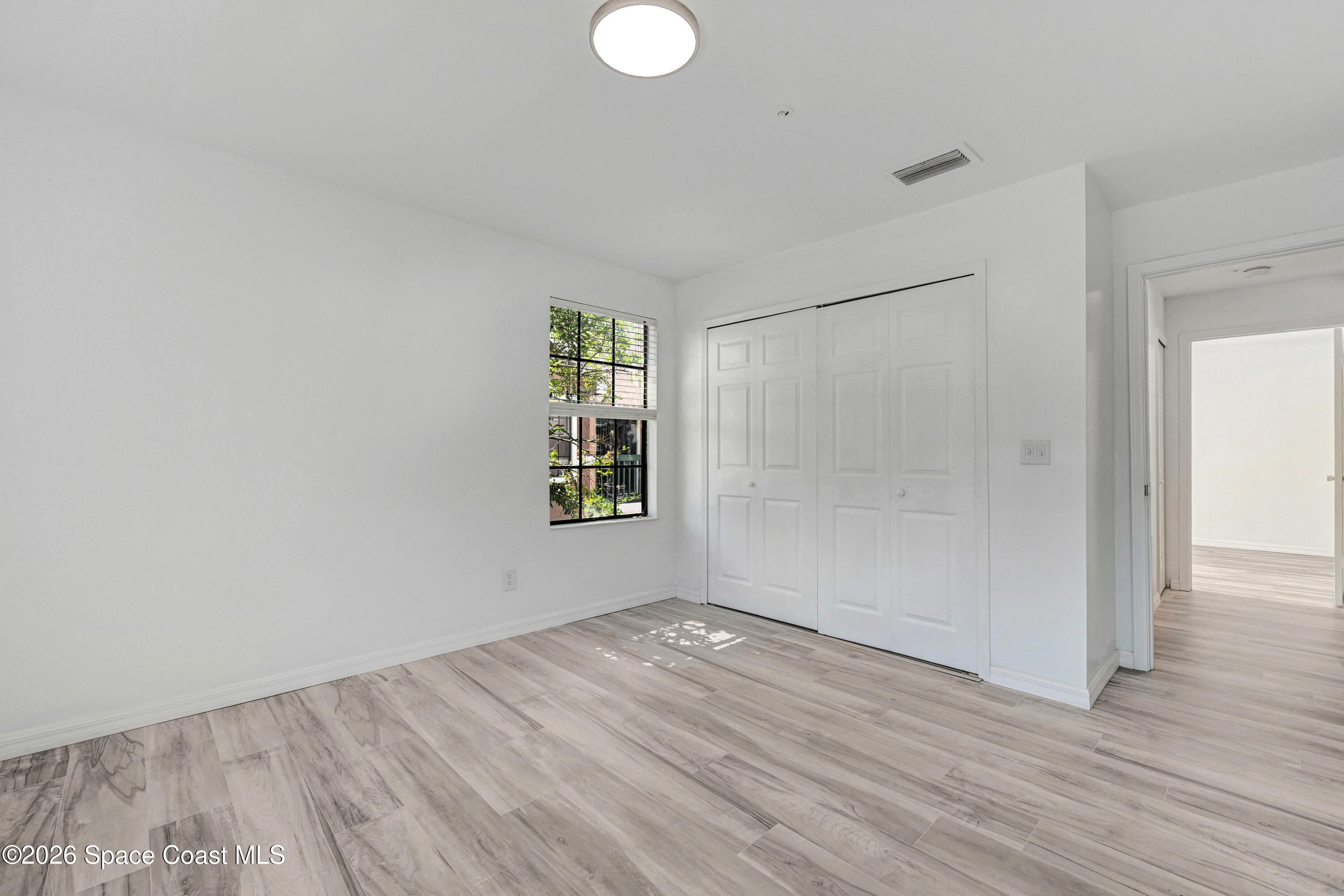 7667 North Wickham Road, Unit 1309 Melbourne, FL 32940 - Photo 14 of 21 an empty room with wooden floor and windows