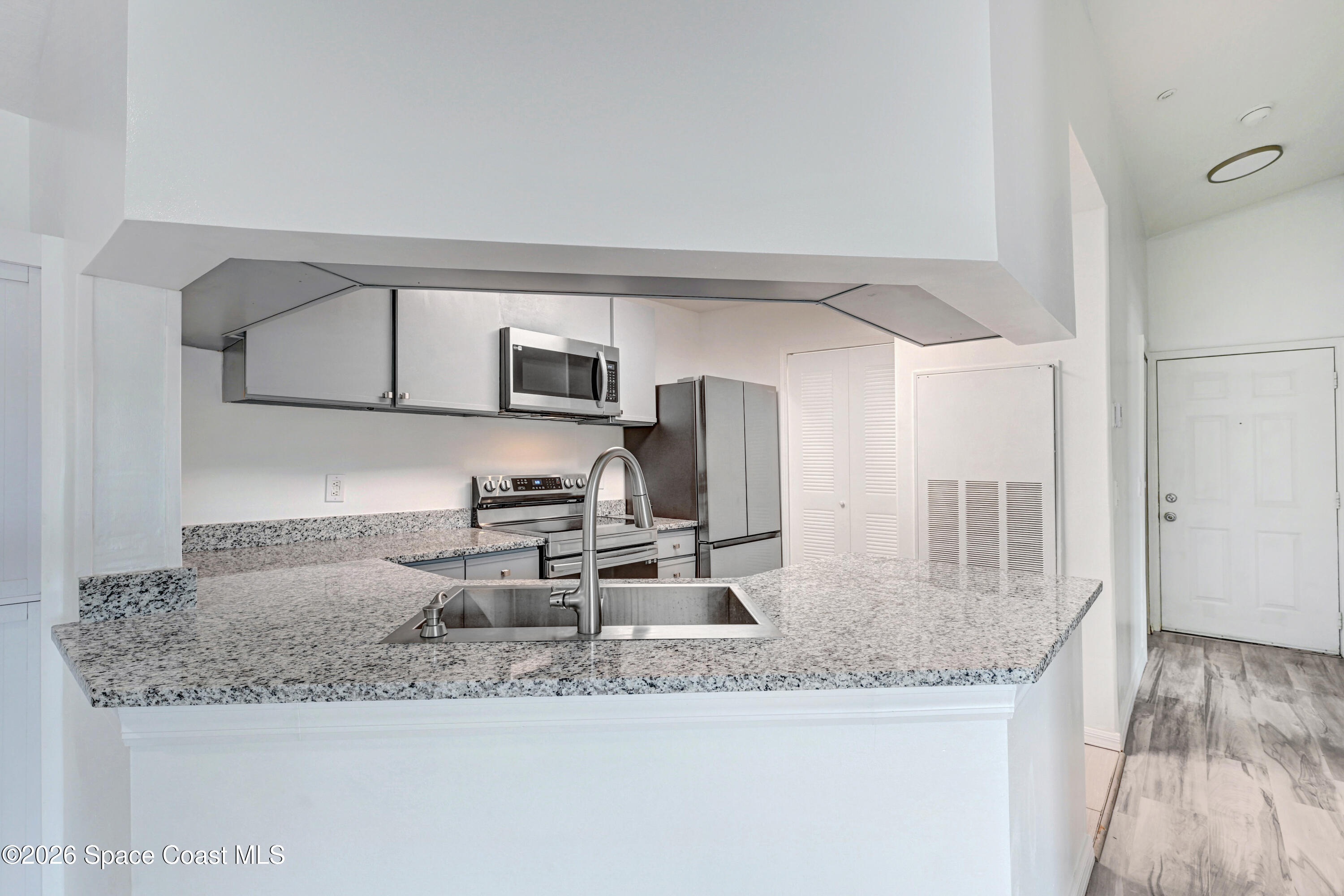 7667 North Wickham Road, Unit 1309 Melbourne, FL 32940 - Photo 4 of 21 a kitchen with granite countertop a sink a stove and a wooden floors