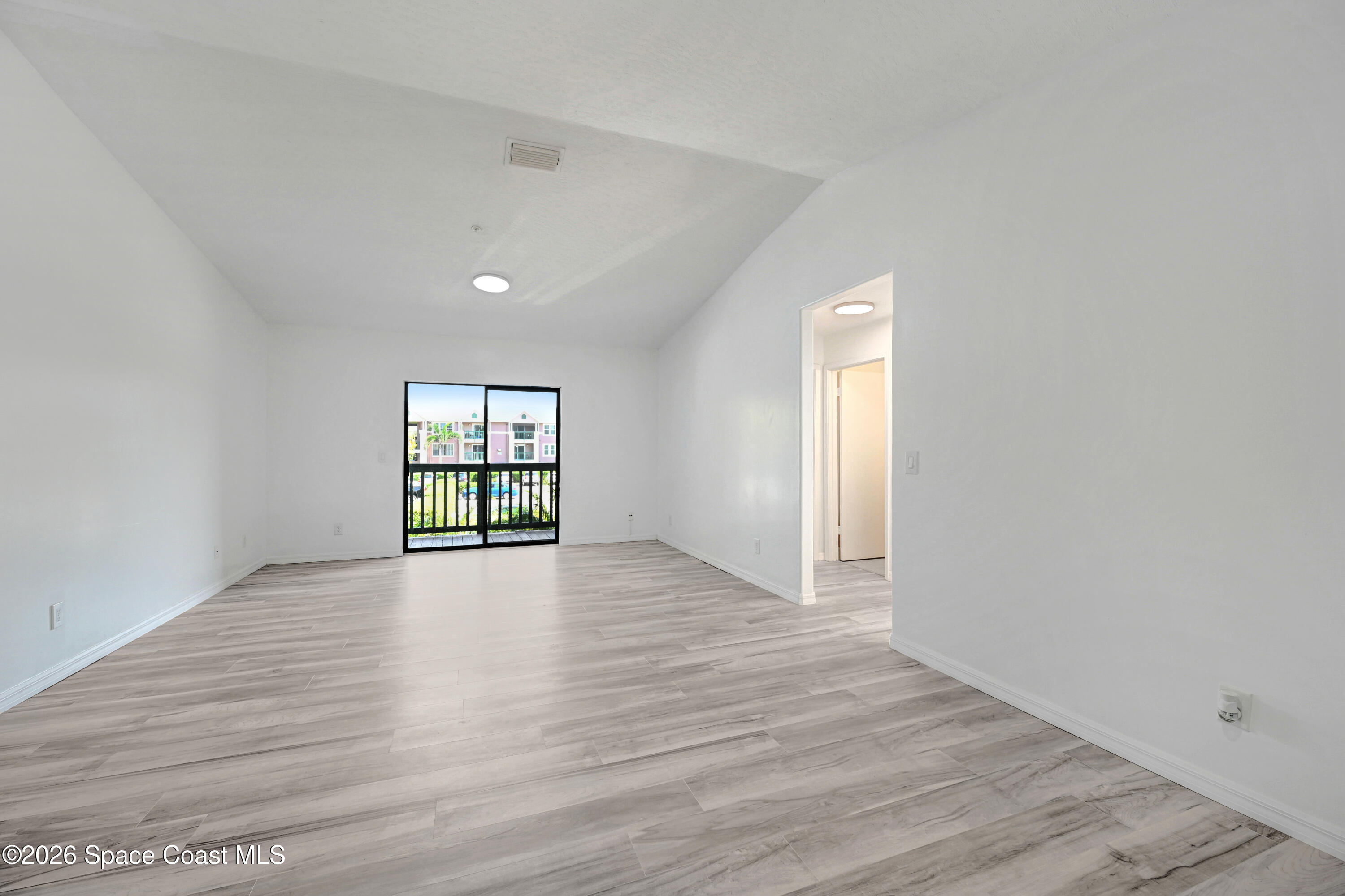 7667 North Wickham Road, Unit 1309 Melbourne, FL 32940 - Photo 9 of 21 an empty room with wooden floor and windows