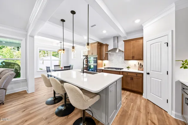 a kitchen with stainless steel appliances granite countertop a kitchen island a table and chairs in it