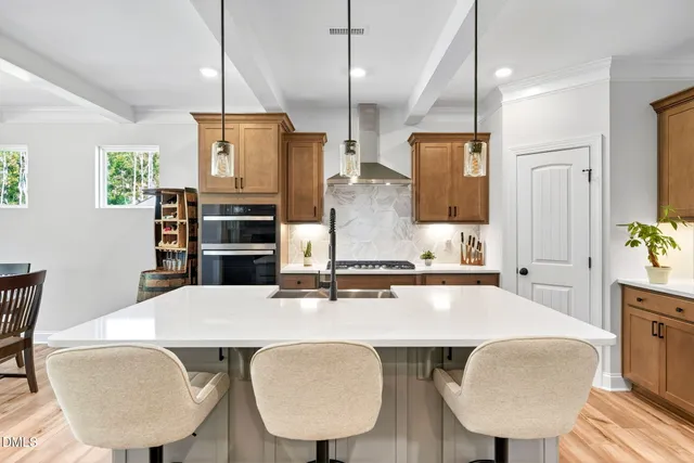 a kitchen with stainless steel appliances kitchen island granite countertop a refrigerator a stove and a sink with wooden floor