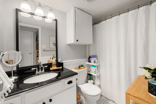 a bathroom with a granite countertop sink vanity mirror and toilet