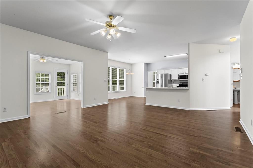 4282 Goldfield Trace, Unit MAIN & 2 Suwanee, GA 30024 - Photo 8 of 28 a view of an empty room with wooden floor and a kitchen