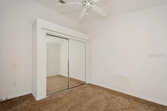 an empty room with windows and fan