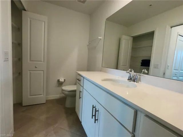 a bathroom with a granite countertop sink a toilet and a large mirror