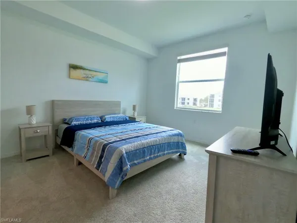 a bedroom with a bed tv and a window