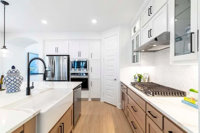 a kitchen with stainless steel appliances a sink a stove top oven a counter space and cabinets