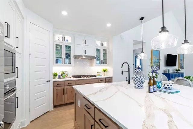 a kitchen with stainless steel appliances kitchen island granite countertop a sink a stove and a wooden floors