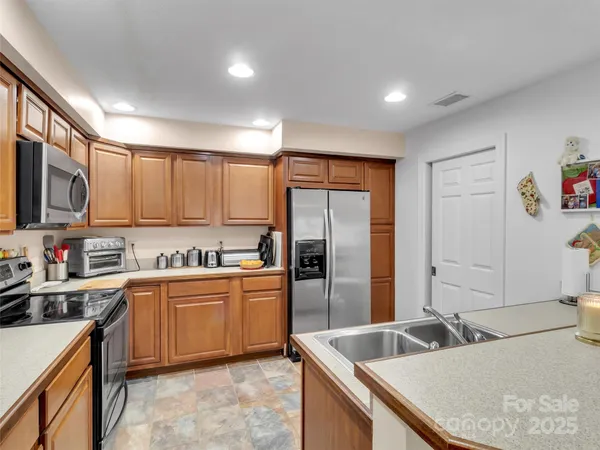 a kitchen with granite countertop a refrigerator sink and stove top oven