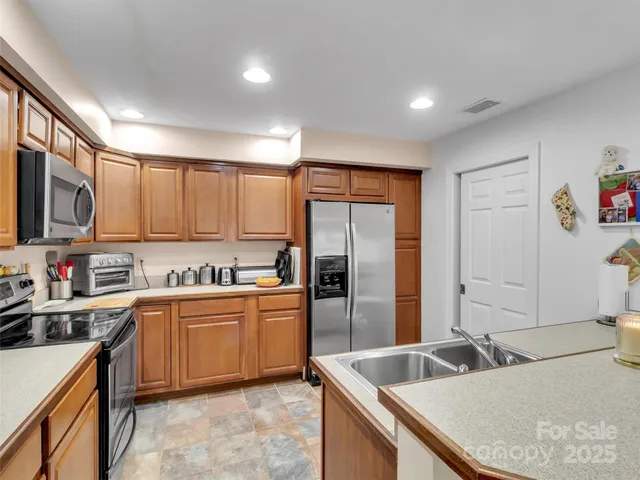 a kitchen with granite countertop a refrigerator sink and stove top oven