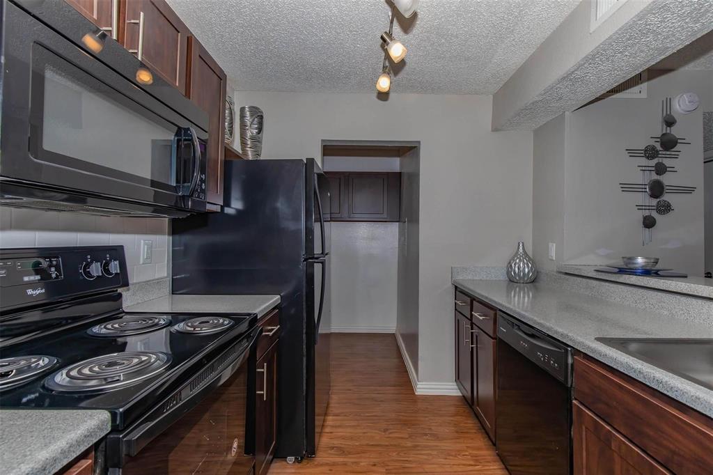 1826 Esters Road, Unit 1050 Irving, TX 75061 - Photo 7 of 39 Kitchen featuring wood-finish flooring, dark wood cabinetry, light-toned countertops, and black appliances